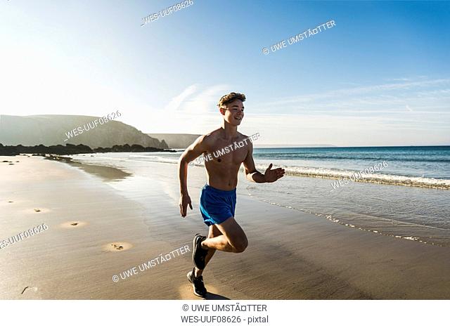 France, Crozon peninsula, young man running on the beach