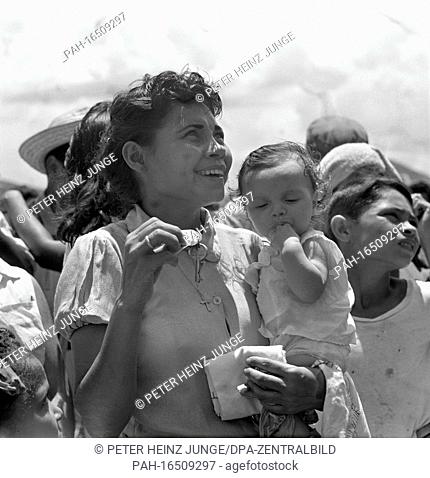A young female peasant with her little daughter on her arm accepts the keys for a new home in a new housing estate in Manzanillo in Oriente Province (Cuba) and...