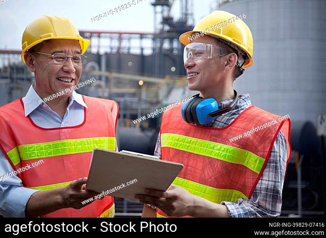 Two engineers in protective workwear standing and laughing outside of a factory