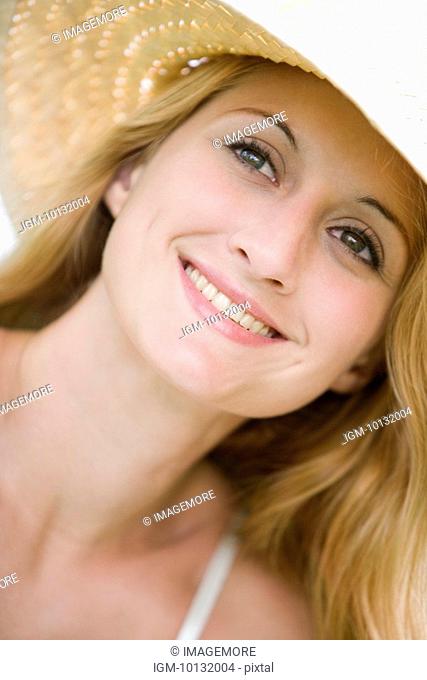 Young woman wearing sunhat, smiling, portrait