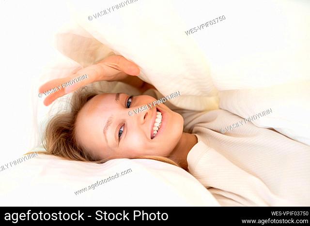 Smiling woman in blanket lying on pillow