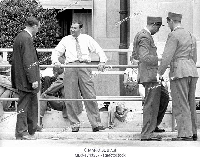 Two men talking leaning on a barrier near two policemen during the proceedings of the Geneva Summit to discuss global security