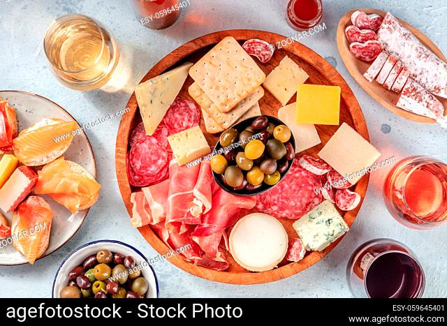 Charcuterie and cheese board with wine, overhead flat lay shot. Italian antipasti or Spanish tapas, shot from above with olives and salmon sanwiches