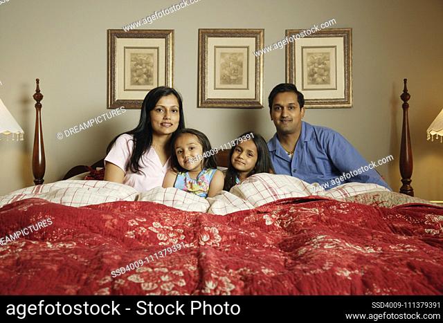 Indian family sitting in bed