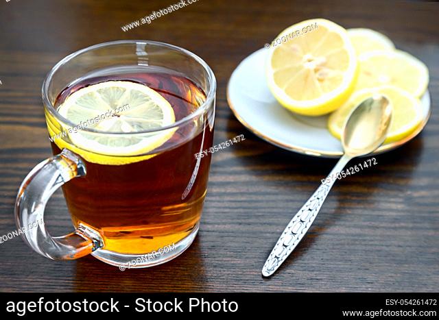 On the surface of the table in a glass Cup hot strong tea and lemon