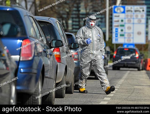 26 March 2020, Poland, Slubice: A man in a protective suit stands with a thermometer on the Stadtbrücke, the German-Polish border crossing from Frankfurt (Oder)...
