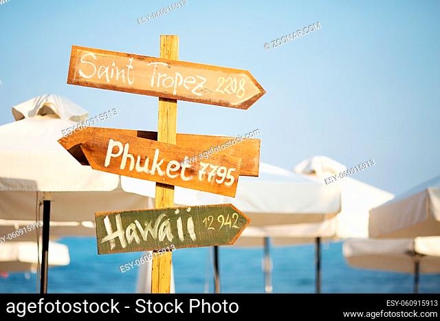 Wooden pointer post with copy space at the beach. arrows on a guidepost pointing at the sea. Signpost showing the way to the beach resorts in front of white...
