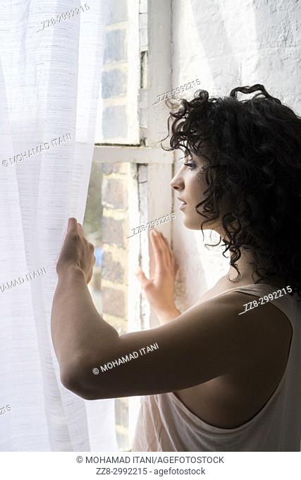 Anxious young woman looking out of the window