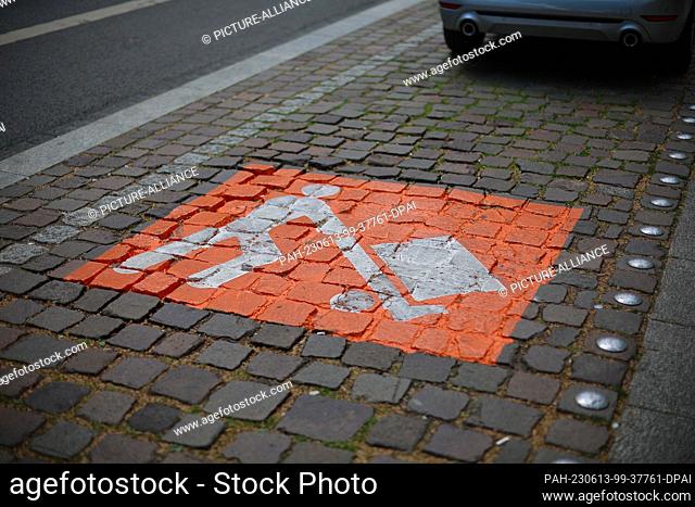 13 June 2023, Saxony, Leipzig: An orange surface with the symbol of a person with a handcart marks a parking space in a delivery zone on Karl-Liebknecht-Strasse