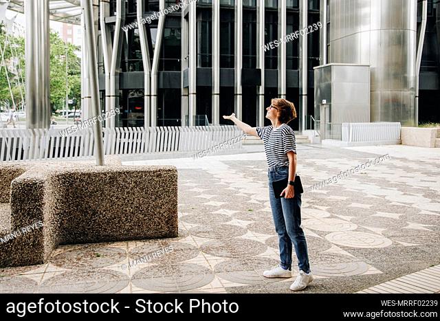 Woman checking for rain standing outside office building