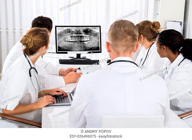 Group Of Doctors Looking At Teeth X-ray On Computer Desktop In Hospital