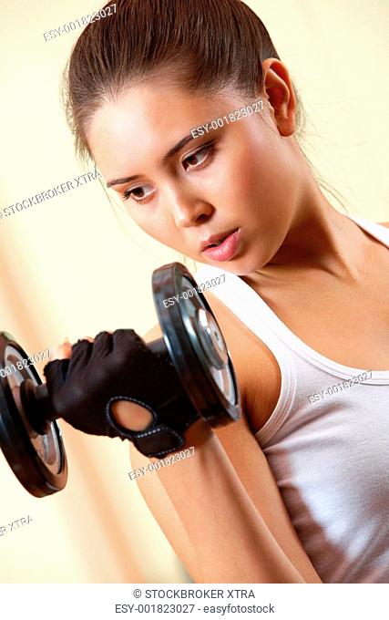 Portrait of young female doing exercises with barbell in gym