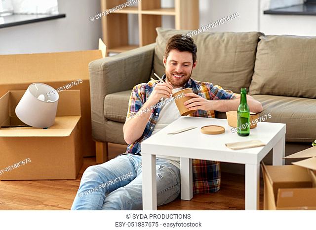 smiling man eating takeaway food at new home