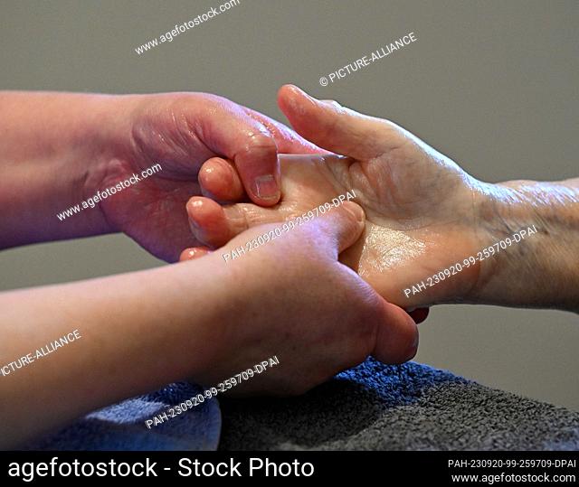 18 September 2023, Brandenburg, Wiesenburg: Britt Muschert, a nurse and aromatherapist, massages the hand of a resident in the DRK's senior citizens'...