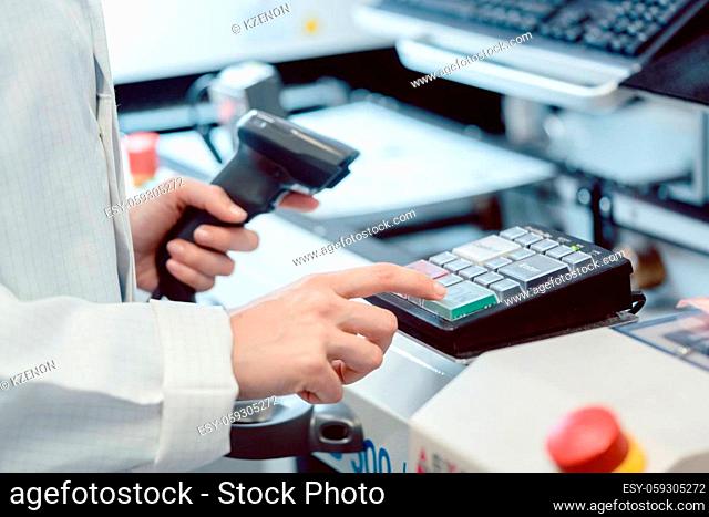Factory worker pressing the OK button on a machine to start production