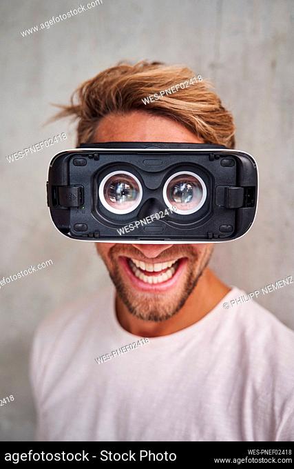 Laughing young man wearing virtual reality goggles