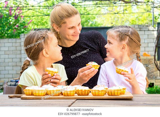 Mother and two daughters sitting at the table with Easter cupcakes in his hands