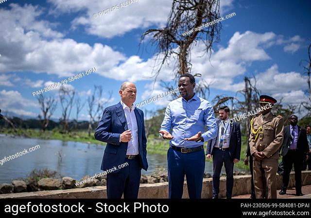 06 May 2023, Kenya, Olkaria: German Chancellor Olaf Scholz (SPD, l) listens to hydrologist Luke Olang explain the ecological and economic changes at Sopa Lodge...