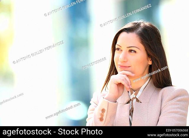 Satisfied businesswoman thinking looking at side outdoors in the street