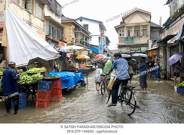 Heavy rain and people marketing in shops on flooded road at Bandra Lane ; Bombay Mumbai ; Maharashtra ; India