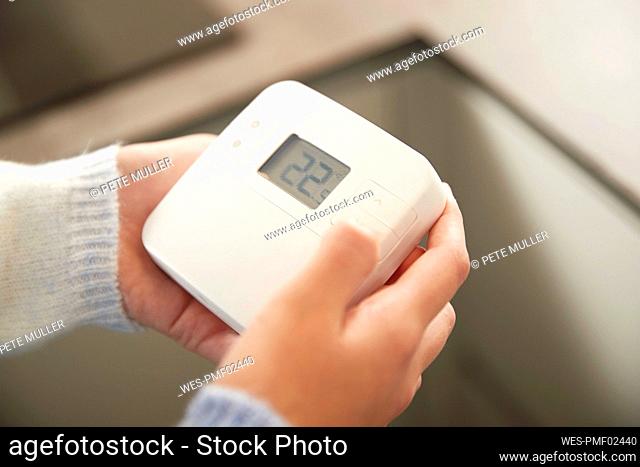 Hands of girl adjusting thermostat at home