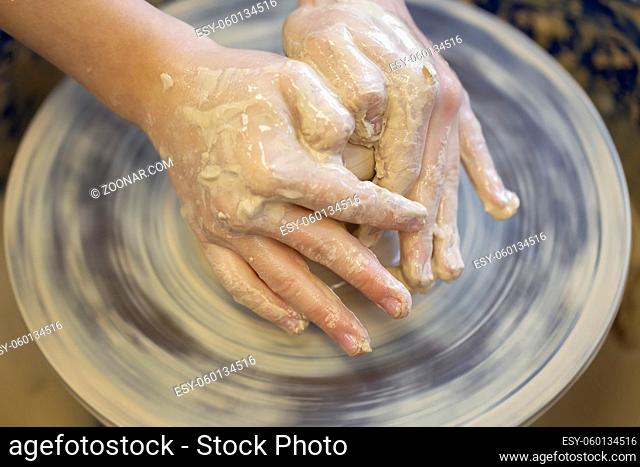 Potter's hands at work. Close-up of a potter's hands with a product on a potter's wheel. Working with clay