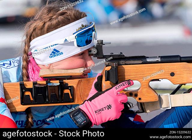 Saint Petersburg biathlete Shishkina Vlada in shooting range. Sportswoman biathlete aiming, rifle shooting in prone position