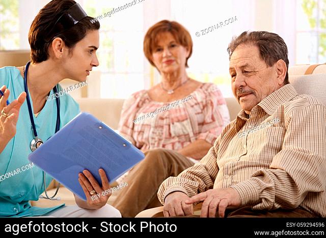 Nurse talking with elderly people showing test results during routine examination at home