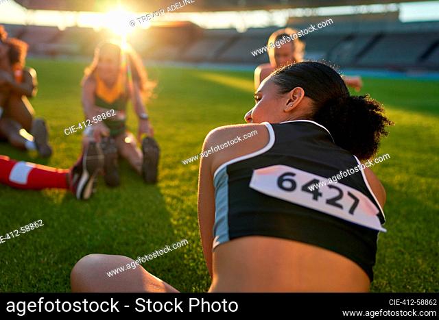 Female track and field athletes stretching before competition