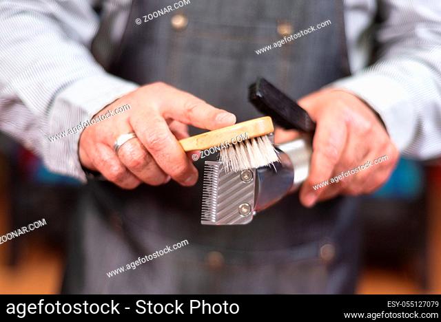 Barber cleaning electric hair clipper at barber shop