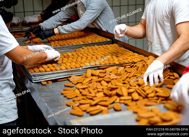 18 December 2023, North Rhine-Westphalia, Aachen: Employees place Printen on a tray at the Nobis Printen bakery. Photo: Henning Kaiser/dpa