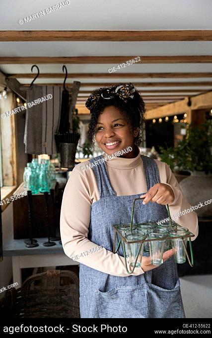 Portrait happy female shop owner holding glass plant holder