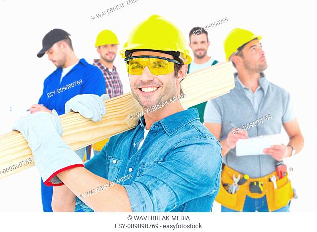 Composite image of carpenter wearing hardhat and glasses while carrying wooden planks