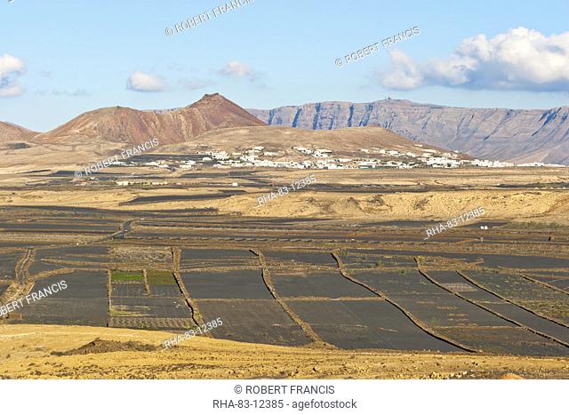 View across black volcanic cinder fields to the town of Soo and the Risco de Famara range with the highest point on the island at Penas del Cache radar site