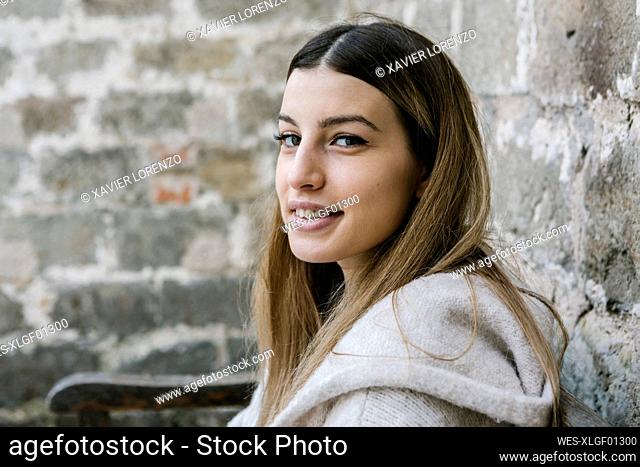 Smiling young woman by wall