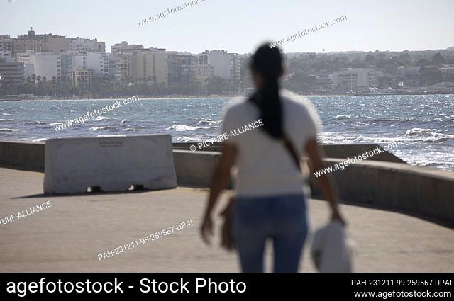 11 December 2023, Spain, Palma: A woman walks along the Arenal beach on a sunny day with a record temperature of 24 degrees. Photo: Clara Margais/dpa