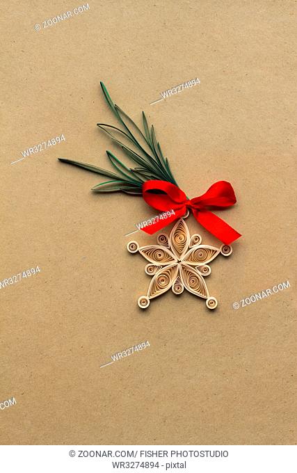 Creative christmas concept photo of a snowflake made of qulling paper on brown background
