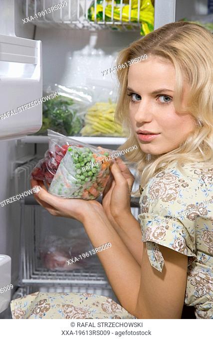 woman put frozen veggies in freezer