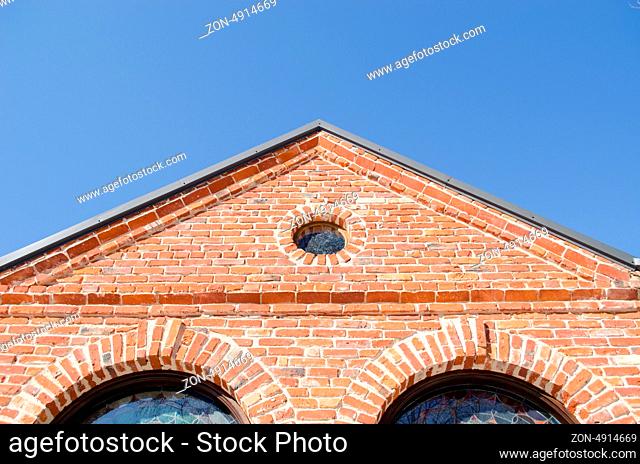 small round window and arch in retro architecture red brick building house roof on background of blue sky