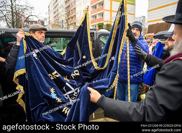 08 December 2023, Saxony-Anhalt, Magdeburg: Participants in the Torah transfer spread out a cloth under which Torah scrolls are to be transferred to the New...
