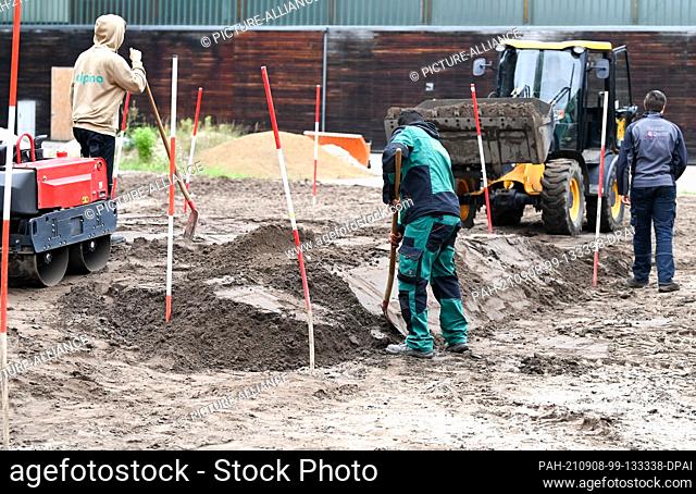 02 September 2021, Brandenburg, Großbeeren: In the Teaching and Research Institute for Horticulture and Arboriculture, trainees carry out earthworks with...
