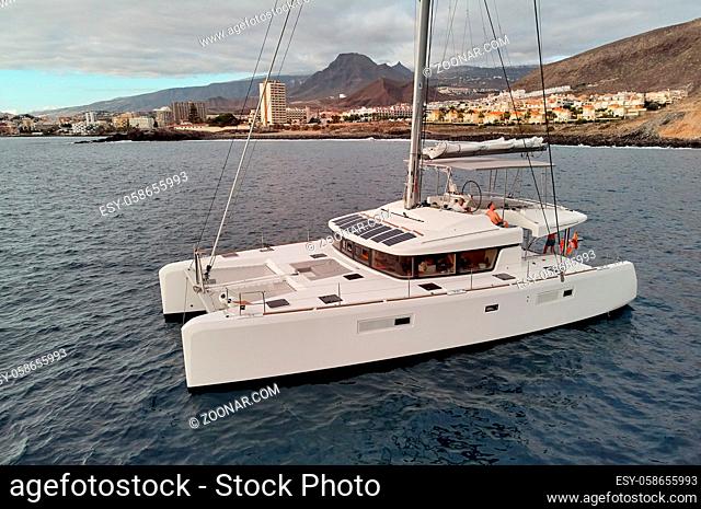 View from above drone point of view of white luxury catamaran in calm water of Atlantic Ocean, Tenerife coastline, Canary Islands Spain