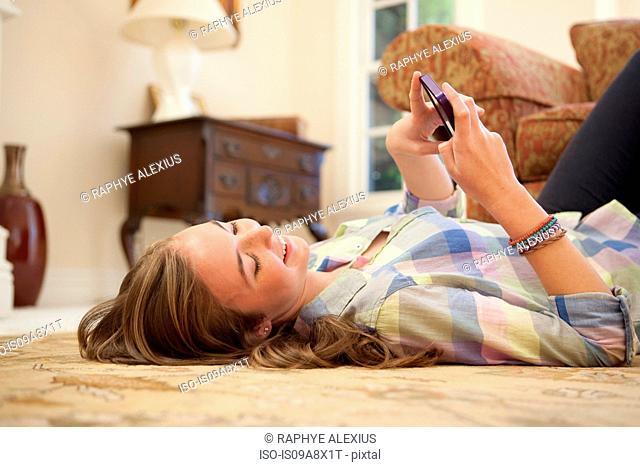 Teenage girl lying on floor with cell phone
