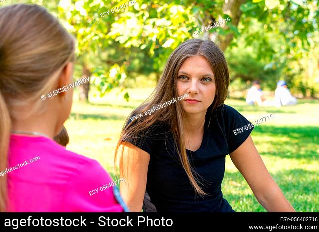 The girl on a picnic listens attentively to the interlocutor