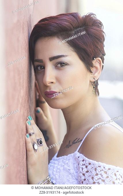 Beautiful young woman leaning against the wall outdoors