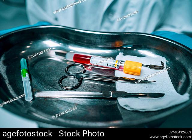 Nurse in rubber gloves holding a tray of surgical medical equipment, close view