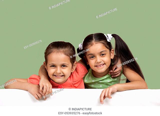 Portrait of smiling sisters over colored background