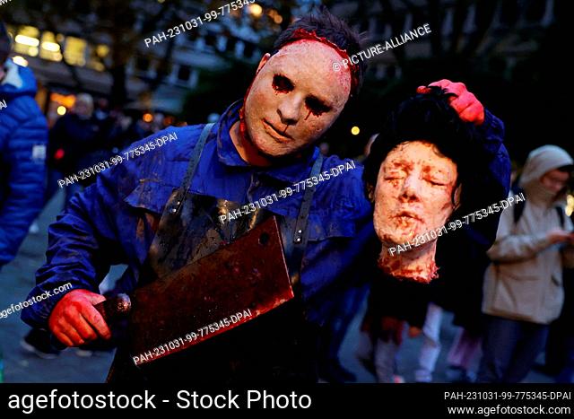 31 October 2023, North Rhine-Westphalia, Essen: Michel Vößing as a butcher zombie with severed head at the Zombie Day in Essen. Photo: David Young/dpa