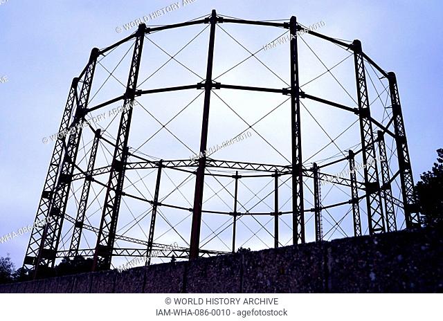 A gas holder. A large container in which natural gas or town gas is stored near atmospheric pressure at ambient temperatures. London