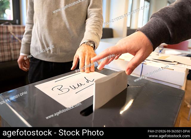 26 September 2021, Berlin: A woman throws her ballot paper for the federal election into a ballot box at a polling station